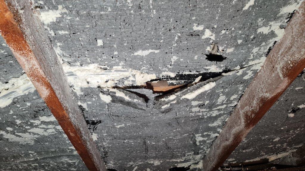 Spray foam over the roof lining, with the covering beneath torn and deteriorating.